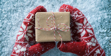Female,Hands,In,Winter,Gloves,With,Christmas,Gift,Box